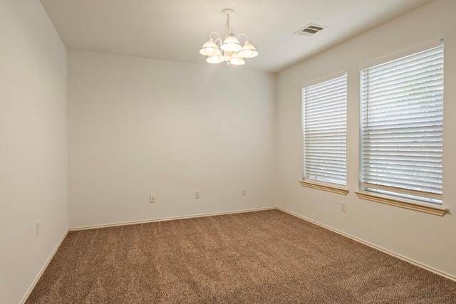 carpeted spare room with a notable chandelier, visible vents, and baseboards