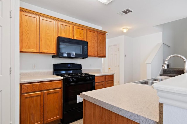 kitchen with visible vents, black appliances, a sink, brown cabinetry, and light countertops