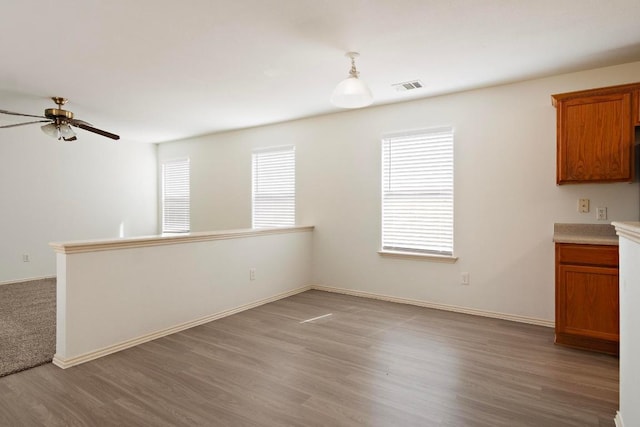 interior space featuring light wood finished floors, visible vents, ceiling fan, light countertops, and brown cabinetry