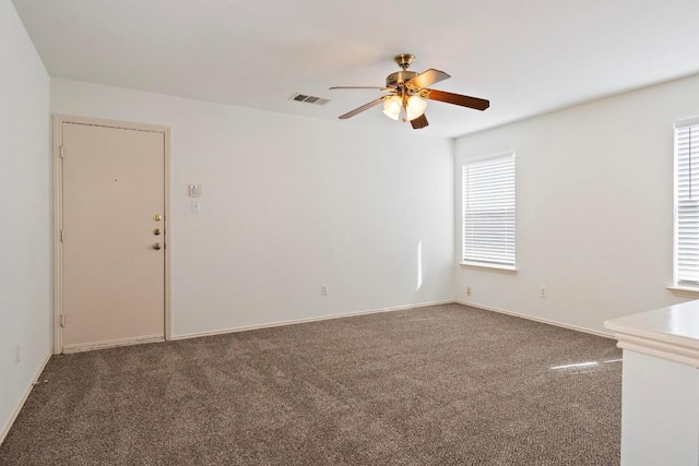 carpeted spare room featuring visible vents, baseboards, and a ceiling fan