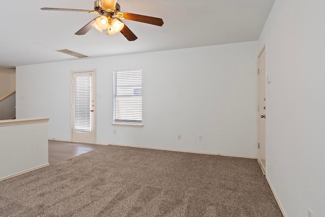 carpeted spare room featuring visible vents, baseboards, and a ceiling fan