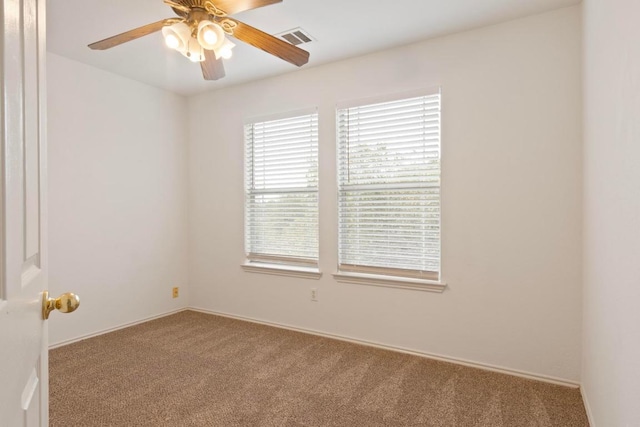 carpeted spare room featuring visible vents and ceiling fan