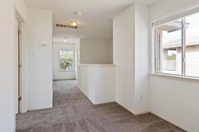 hall with visible vents, baseboards, and carpet