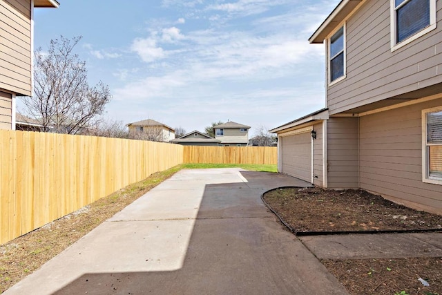 view of yard featuring concrete driveway, fence, and a garage