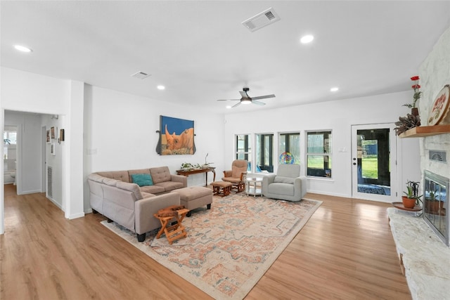 living room featuring recessed lighting, visible vents, light wood-style floors, and a stone fireplace