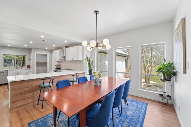 dining space featuring washing machine and clothes dryer, a healthy amount of sunlight, light wood finished floors, and baseboards