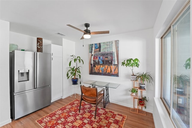 interior space with baseboards, stainless steel fridge, light wood-style flooring, and white cabinets