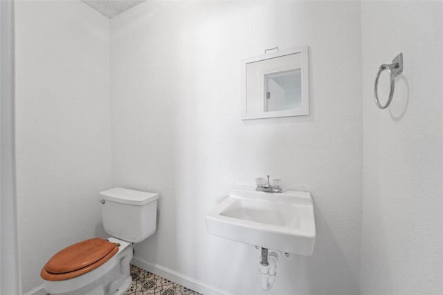 bathroom with toilet, baseboards, and a sink