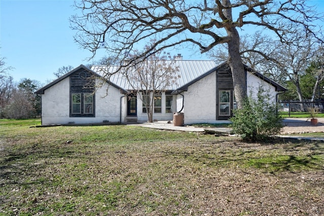 view of front of home with a front lawn, a chimney, and metal roof