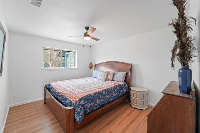 bedroom with ceiling fan, visible vents, baseboards, and wood finished floors