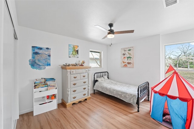 bedroom featuring baseboards, visible vents, light wood finished floors, and ceiling fan