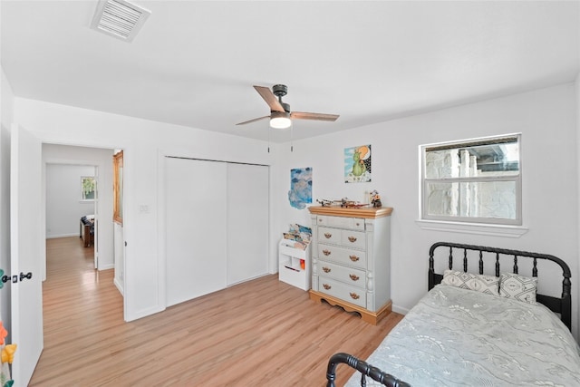 bedroom with light wood finished floors, visible vents, multiple windows, and a closet