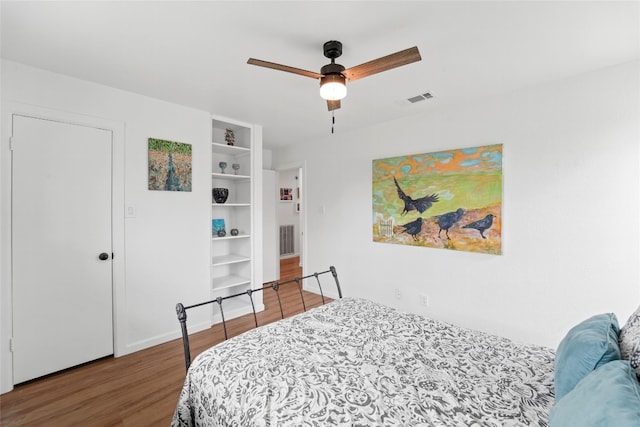 bedroom featuring a ceiling fan, wood finished floors, visible vents, and baseboards