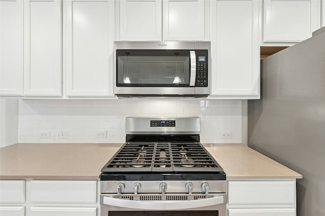 kitchen featuring tasteful backsplash, appliances with stainless steel finishes, and white cabinetry