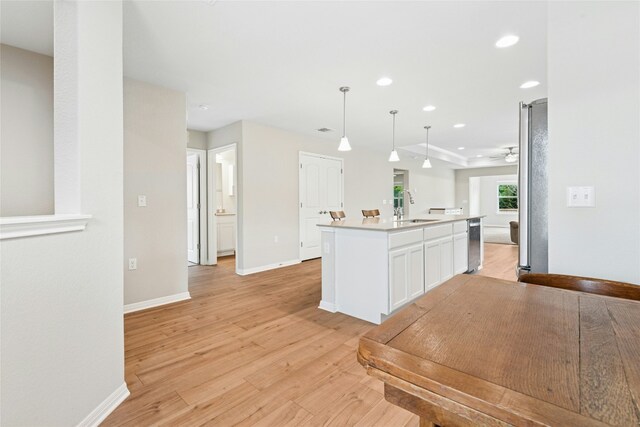 kitchen with baseboards, recessed lighting, light wood-style flooring, white cabinetry, and a sink