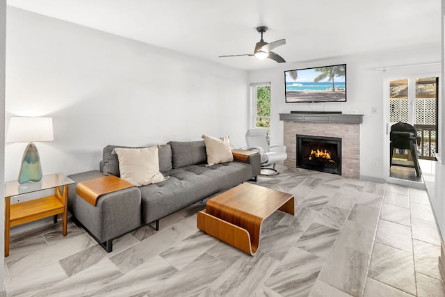 living area featuring a lit fireplace and ceiling fan