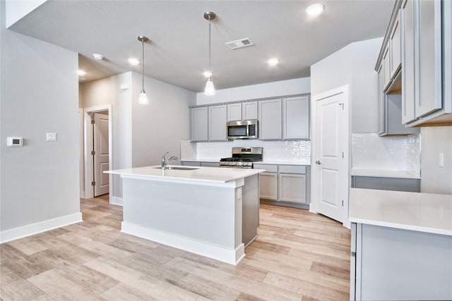 kitchen with light wood-type flooring, visible vents, gray cabinets, a sink, and stainless steel appliances