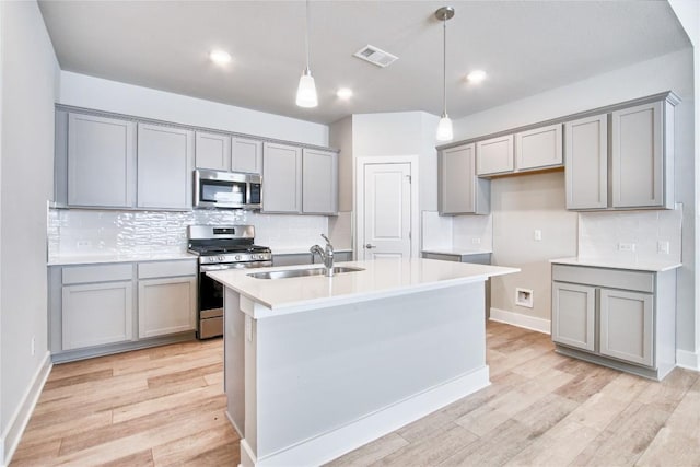 kitchen with visible vents, gray cabinetry, stainless steel appliances, and a sink