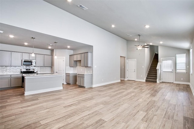 unfurnished living room featuring visible vents, light wood finished floors, baseboards, ceiling fan, and stairs