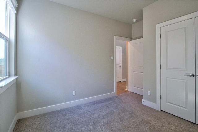 unfurnished bedroom with baseboards and light colored carpet