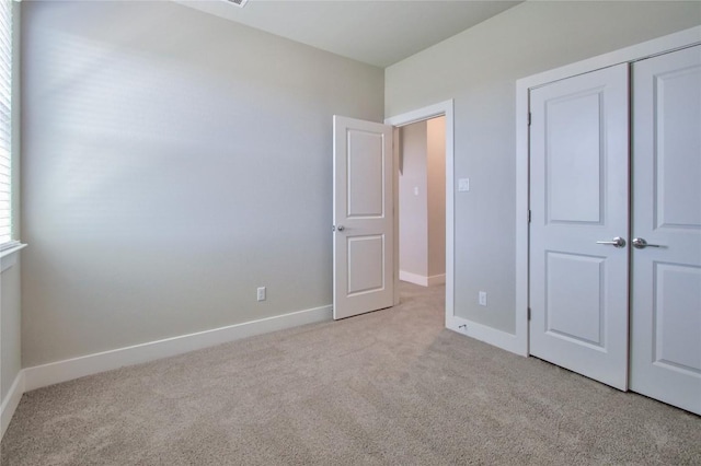 unfurnished bedroom with carpet, baseboards, and a closet