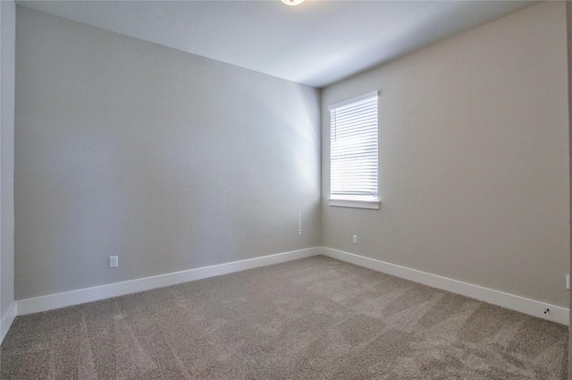 unfurnished room featuring baseboards and light carpet