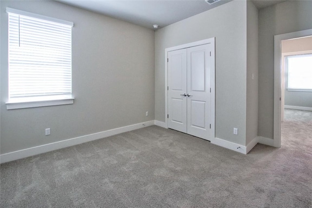 unfurnished bedroom with baseboards, carpet floors, and a closet