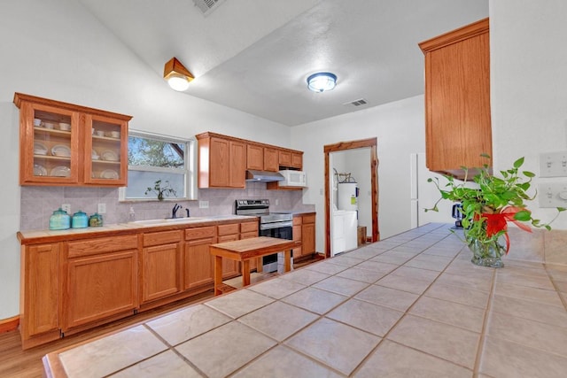 kitchen featuring visible vents, a sink, electric stove, under cabinet range hood, and backsplash