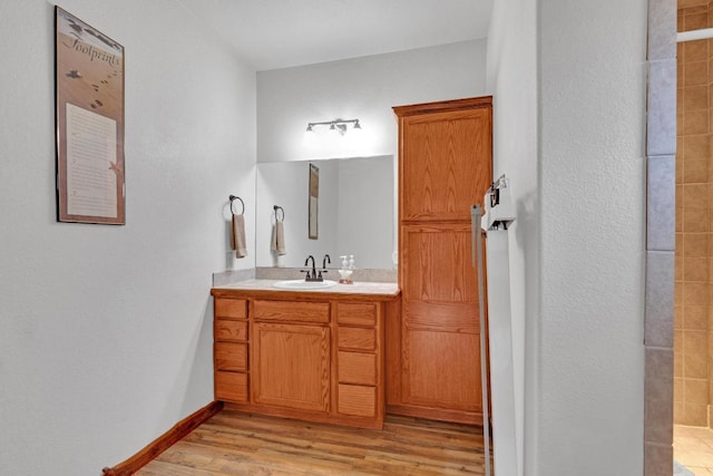 full bath featuring baseboards, wood finished floors, and vanity