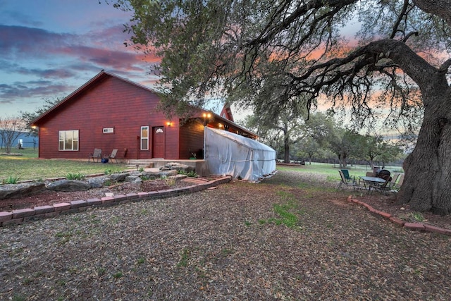 property exterior at dusk with a patio area and a lawn