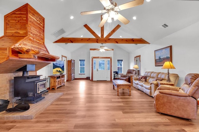 living room with visible vents, light wood-style floors, and a wood stove