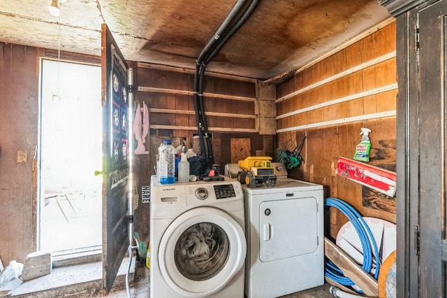 laundry area with laundry area, separate washer and dryer, a garage, and wood walls