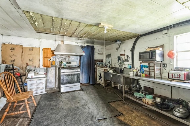 kitchen with stainless steel appliances, concrete block wall, and exhaust hood