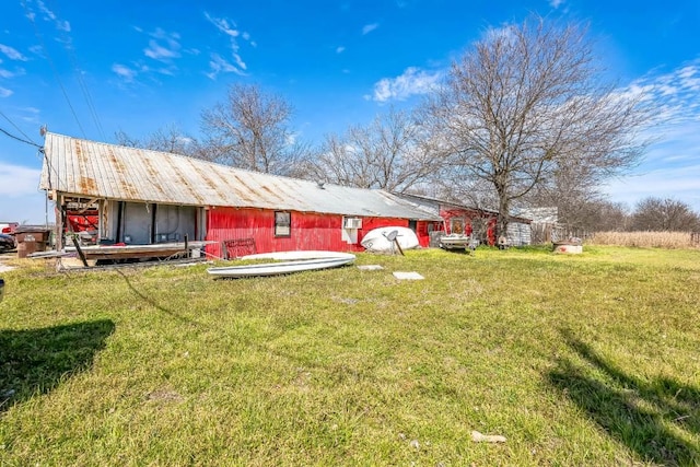 rear view of property featuring an outbuilding, a lawn, and an outdoor structure