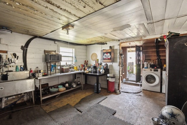 below grade area with washing machine and clothes dryer, wooden ceiling, a garage, concrete block wall, and a sink