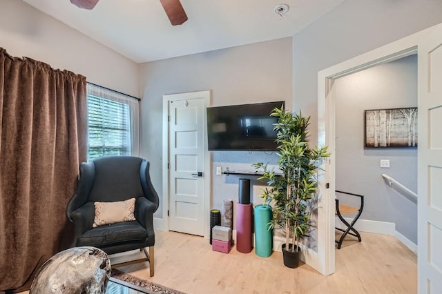 sitting room with light wood-type flooring, baseboards, and a ceiling fan