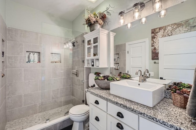 bathroom featuring vanity, toilet, and a tile shower