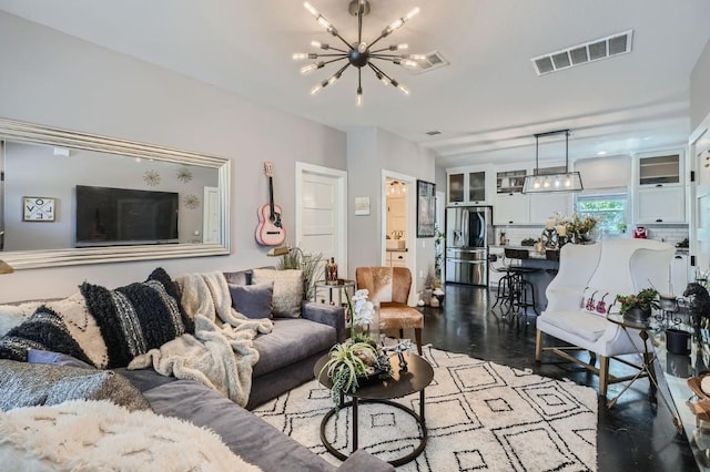 living room with visible vents, an inviting chandelier, and wood finished floors