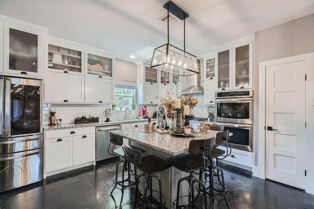 kitchen with a center island, decorative backsplash, white cabinets, and stainless steel appliances