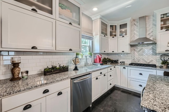 kitchen featuring a sink, light stone counters, white cabinets, wall chimney range hood, and dishwasher