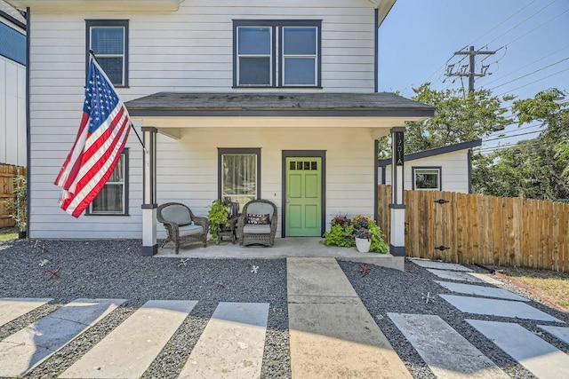 view of front of property with fence, covered porch, and a shingled roof