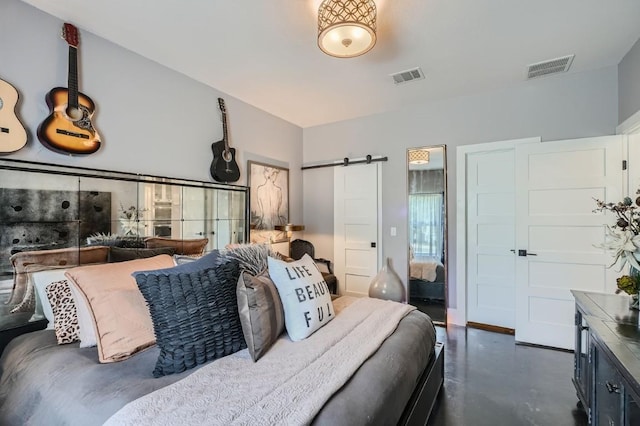 bedroom with a barn door, visible vents, and finished concrete flooring