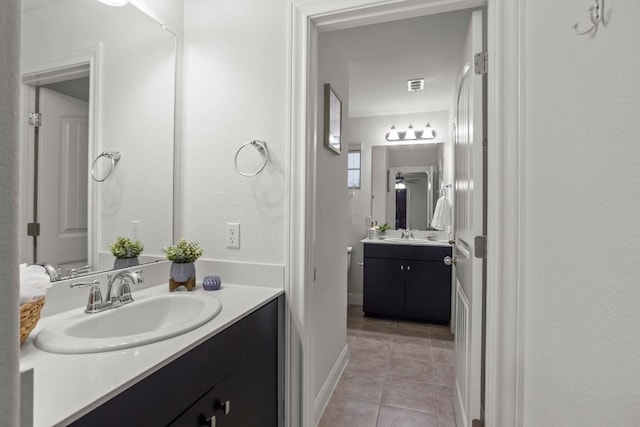 bathroom featuring tile patterned floors, visible vents, two vanities, and a sink