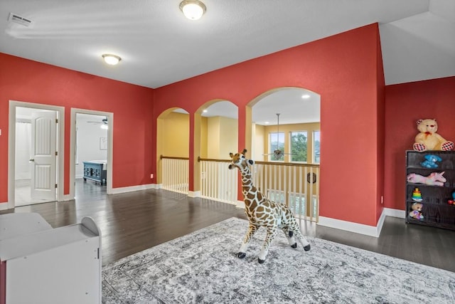 interior space with a ceiling fan, wood finished floors, visible vents, and baseboards