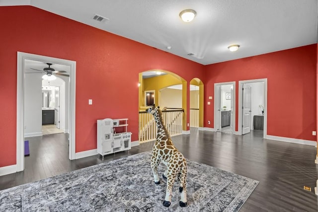 game room with visible vents, baseboards, vaulted ceiling, wood finished floors, and arched walkways