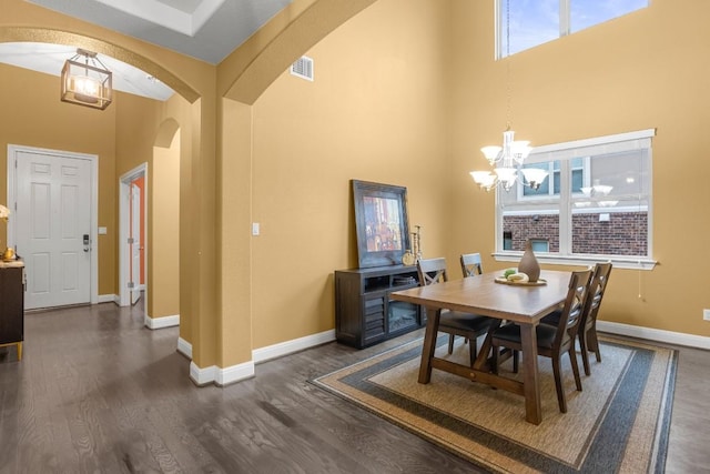 dining area with arched walkways, visible vents, baseboards, and dark wood-style flooring