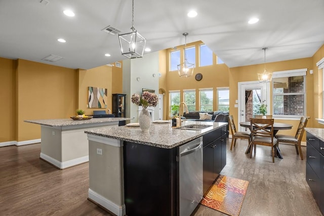 kitchen with visible vents, a center island with sink, a sink, stainless steel dishwasher, and dark cabinets