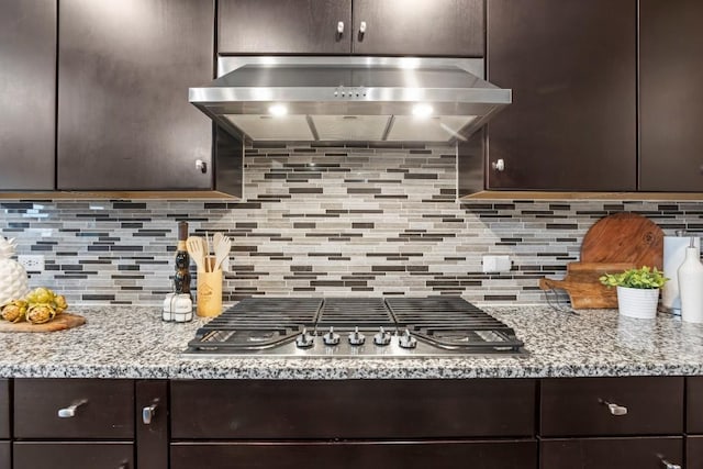 kitchen with dark brown cabinets, range hood, decorative backsplash, and stainless steel gas stovetop