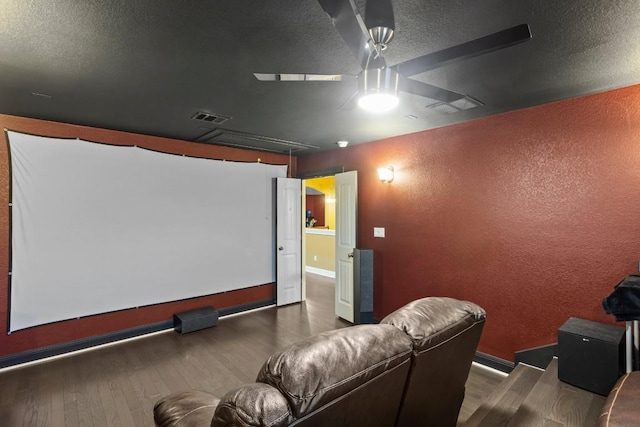 cinema featuring wood finished floors, visible vents, a textured wall, and a textured ceiling