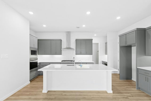 4419 College Square Dr, Round Rock, TX 78665 - kitchen featuring decorative backsplash, oven, a center island with sink, wall chimney range hood, and gray cabinetry